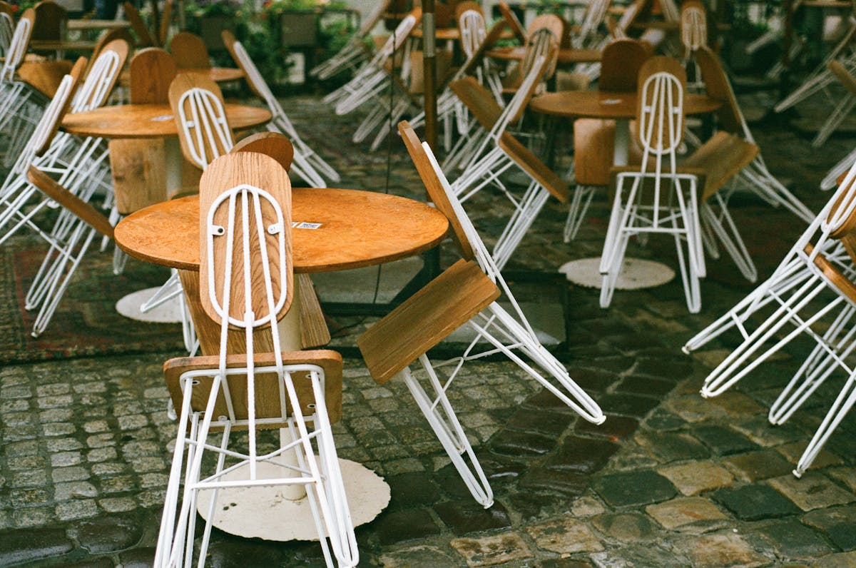 Terrasse de caf&eacute; sur une rue pav&eacute;e de Lviv avec tables en bois